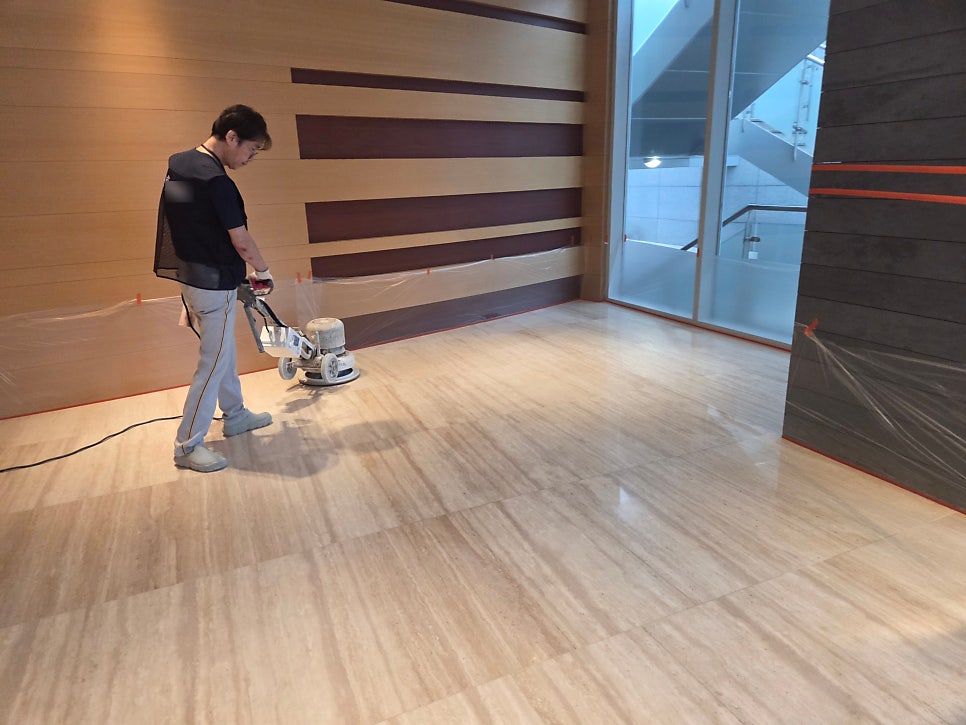 작업자가 벽면 근처에서 연마기로 작업 중