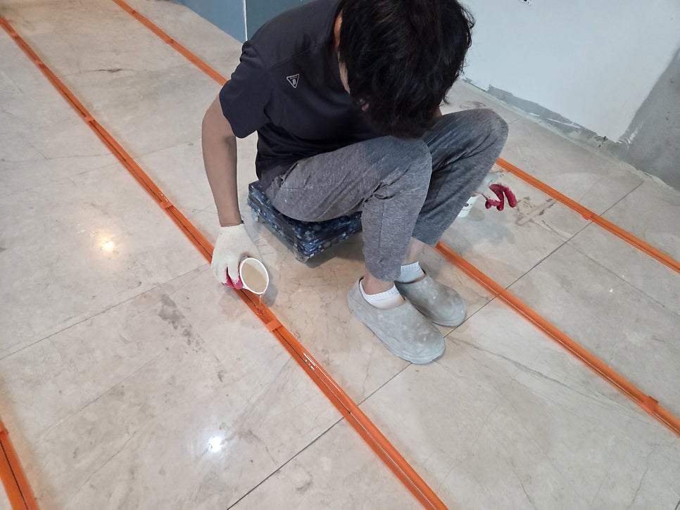 작업자가 벽 가장자리 줄눈을 수공구로 제거 중